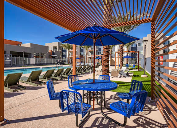 A blue umbrella is on a table with chairs around it.