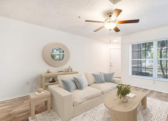 A living room with a beige couch, a wooden coffee table, and a round mirror on the wall.