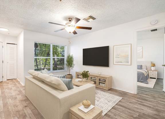 A living room with a couch, a television, and a ceiling fan.