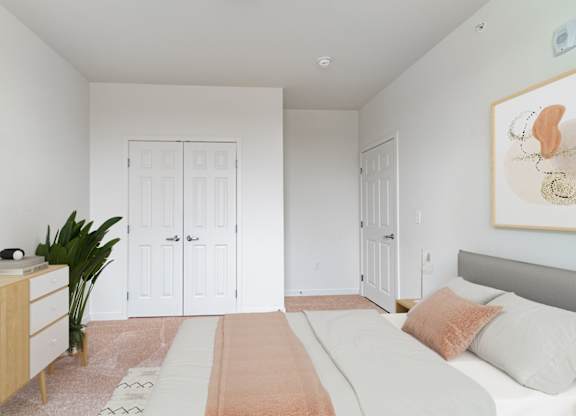 A bedroom with a bed, dresser, and a plant.