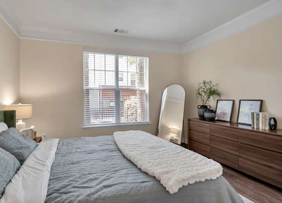 A bedroom with a large bed and a window with blinds.
