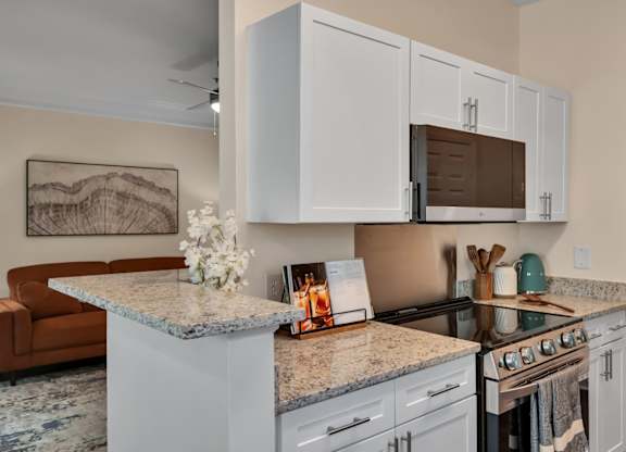 A kitchen with granite countertops and white cabinets.
