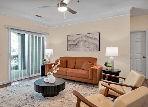 A living room with a brown couch, a coffee table, and a ceiling fan.