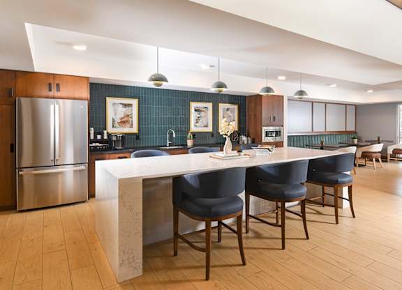A modern kitchen with a large island and chairs.
