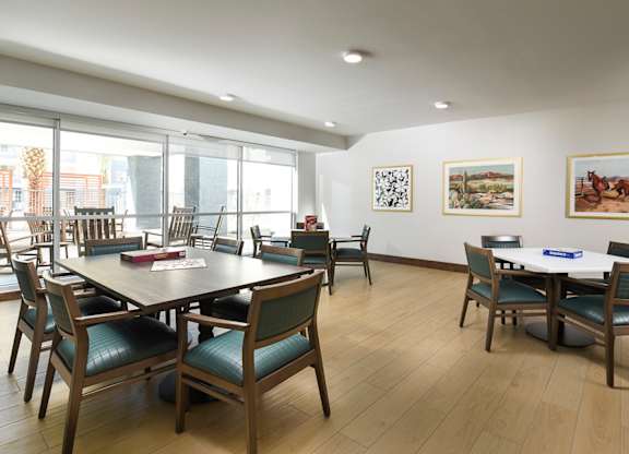 A room with a table surrounded by chairs and pictures on the wall.