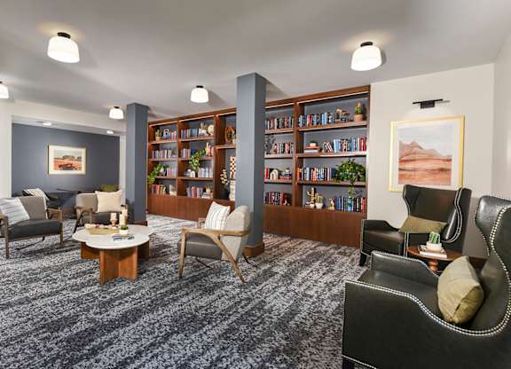 A living room with grey carpet and a bookshelf filled with books.
