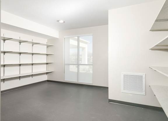 A room with a window and shelves on the wall.
