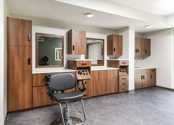 A chair is in front of a wooden cabinet with a mirror.