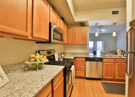 a kitchen with wooden cabinets and granite counter tops at Mariposa at Cedars of Elk Drive 55+ Apartments, Burleson