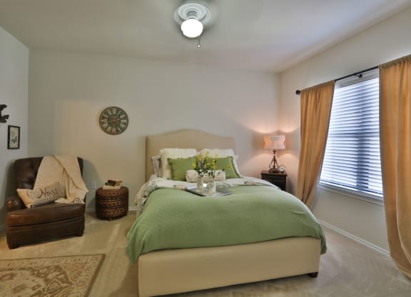 a bedroom with a bed and a chair and a clock on the wall