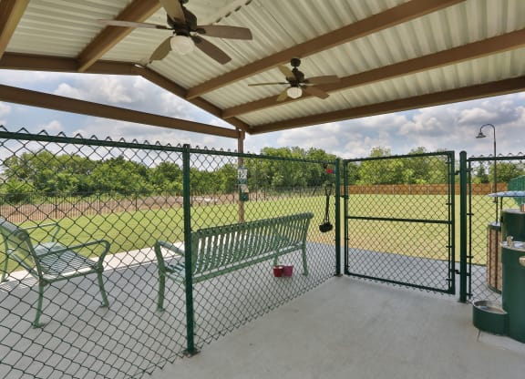 a patio with a bench and a chain link fence at Cedars of Elk Drive 55+ Apartments, Burleson, TX