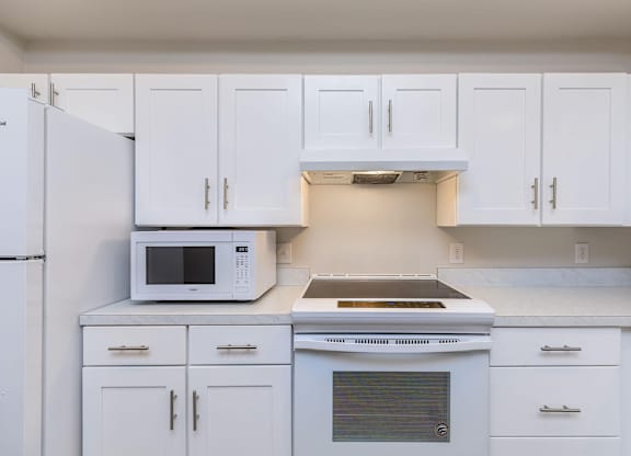 a kitchen with white cabinets and a microwave and a stove at Mariposa at Westchester, Texas, 75052