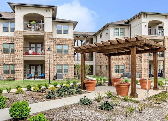 an outdoor area with potted plants in front of an apartment building at Mariposa at Westchester, Grand Prairie, 75052