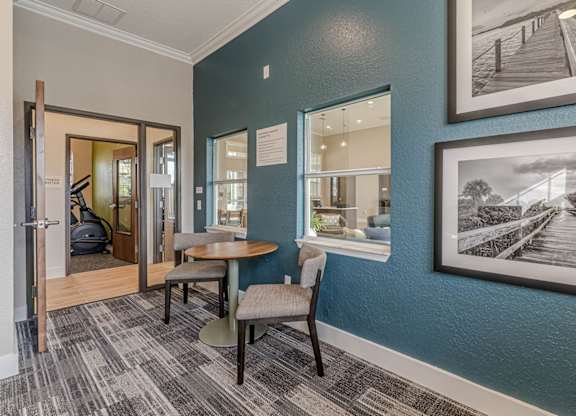 A room with a table and chairs and a painting on the wall.
