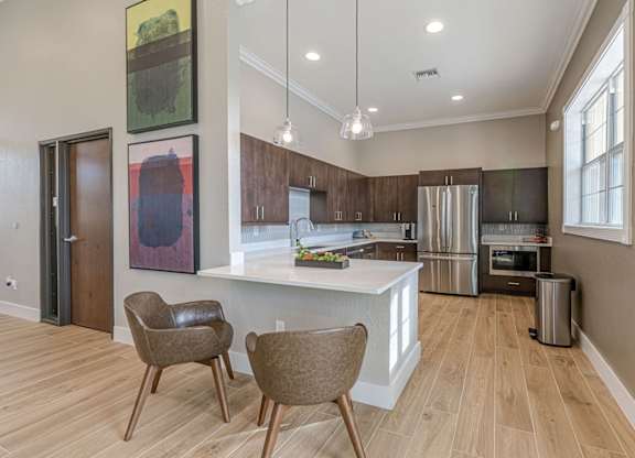 A kitchen with a white island and brown chairs.