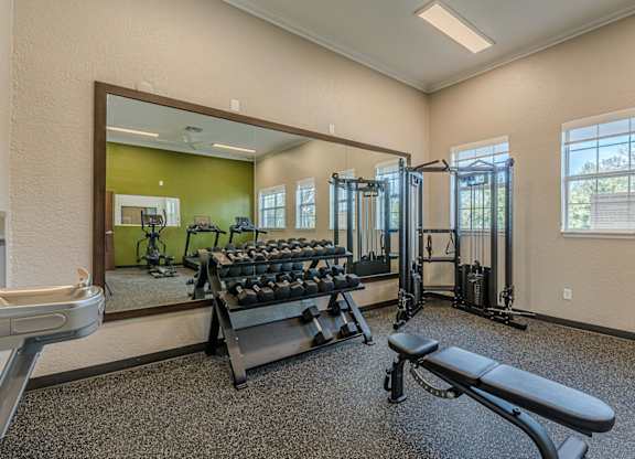 A gym with a mirror, weights, and exercise equipment.