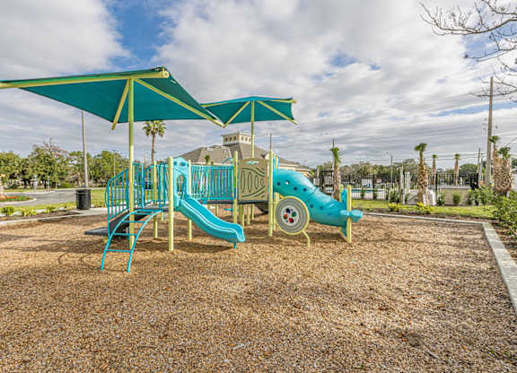 A playground with a blue slide and a green canopy.
