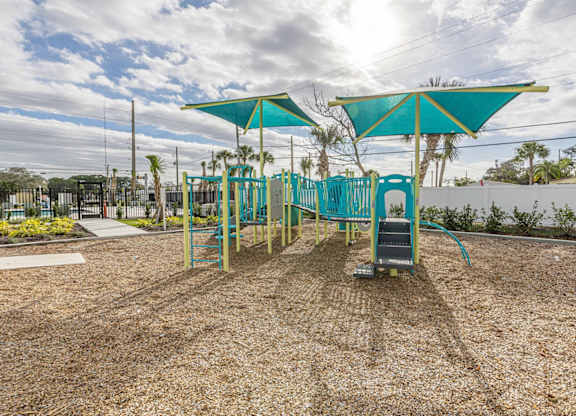 A playground with a blue canopy and a slide.
