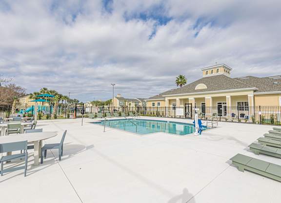A pool area with sun loungers and a building in the background.