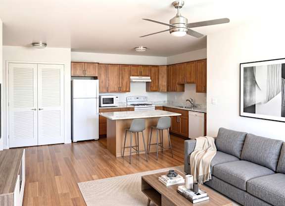 A modern kitchen with a dining table and a grey sofa.