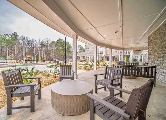 A patio with a table and chairs under a roof.