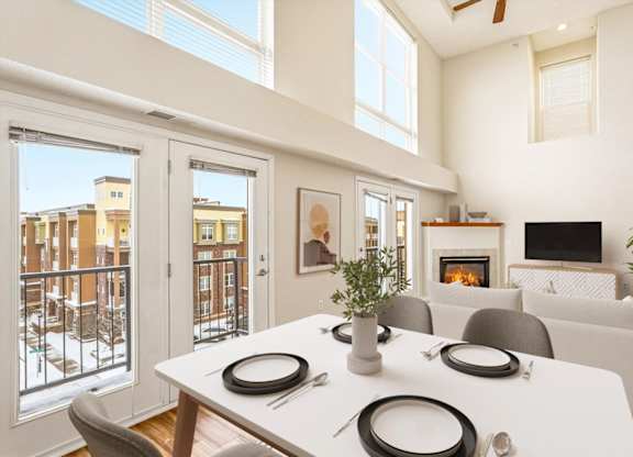 A dining table with four place settings is in the middle of a living room.