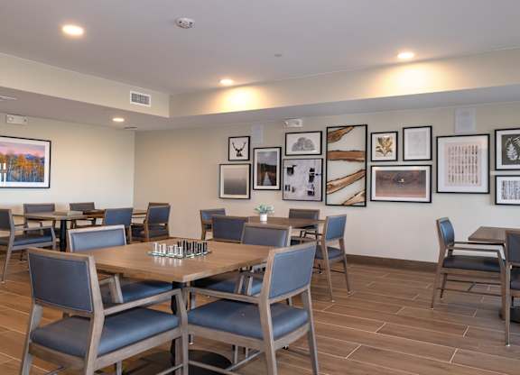 A dining room with a long table surrounded by chairs.