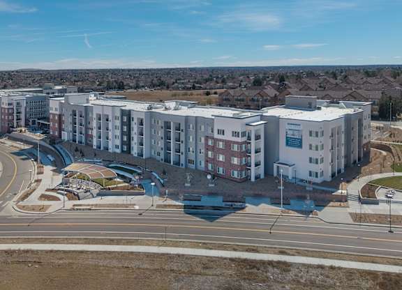 A large apartment complex with a parking lot in front.