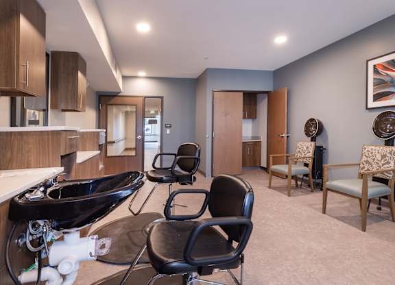 A bathroom with a black sink and two chairs.