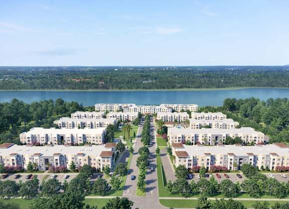 A large housing complex with a lake in the background at The Mira Apartments, Apopka, FL
