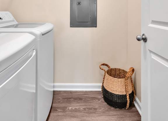 A laundry room with a washer and dryer and a basket on the floor.