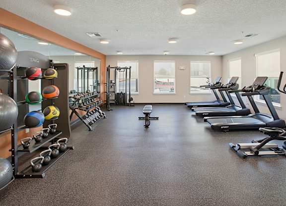 A gym with a variety of equipment including treadmills, weights, and exercise machines.