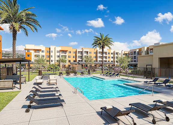Pool area with sun loungers and palm trees at Vivir at Ballpark Village Apartments, Arizona, 85338