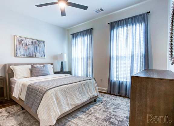 a bedroom with a bed and two windows and a ceiling fan