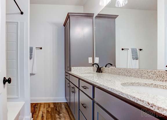 A bathroom with a white counter top and a brown cabinet.