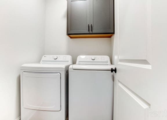 a washer and dryer in a laundry room with a cabinet and a door