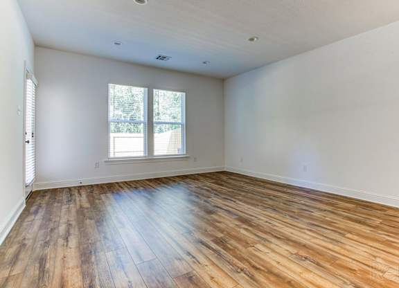 an empty living room with wood flooring and a window