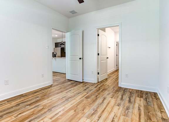 an empty living room with wood floors and white walls