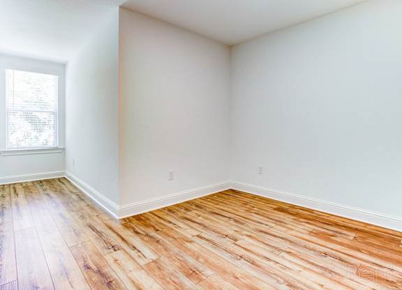 an empty room with wood floors and a window