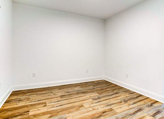 an empty room with wood floors and white walls