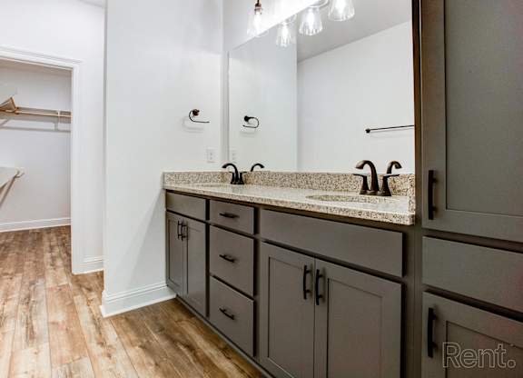a bathroom with gray cabinets and a sink and a mirror