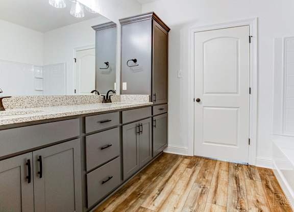 a bathroom with gray cabinets and a white door