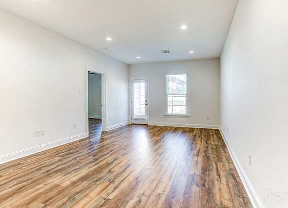 the living room and dining room with hardwood flooring and white walls