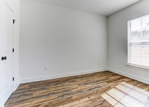 an empty room with wood floors and a window