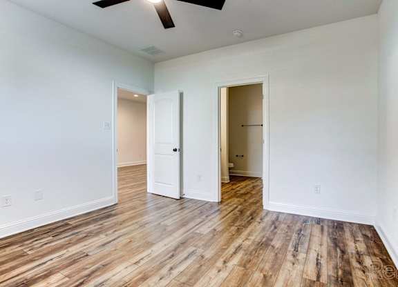 an empty living room with wood floors and white walls