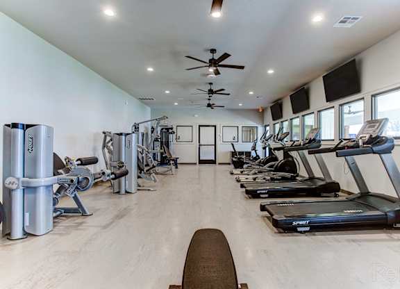 a gym with treadmills and other exercise equipment in a building with windows