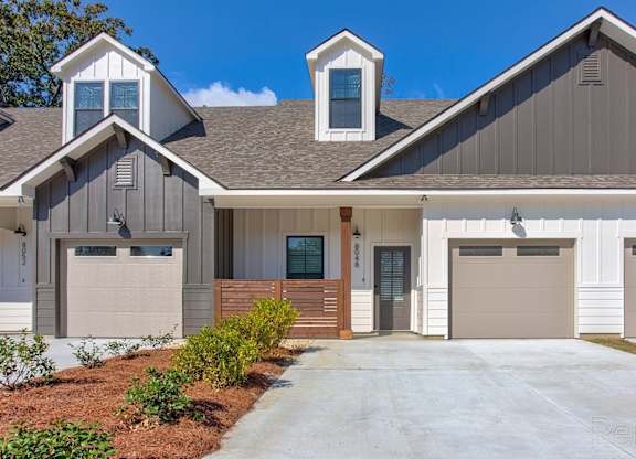 the front of a house with two garage doors and a driveway