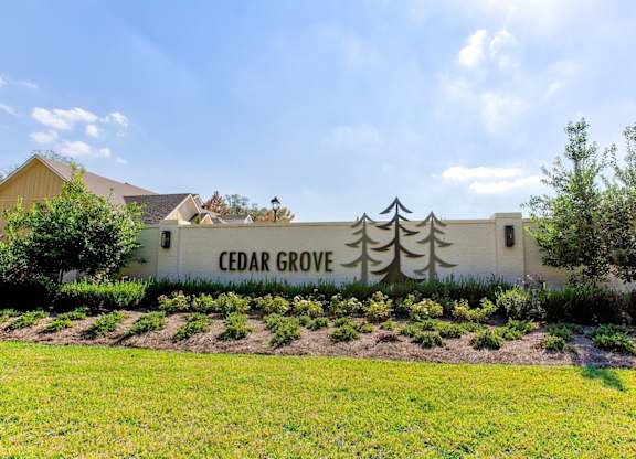 a sign for cedar grove sits in front of a grass field