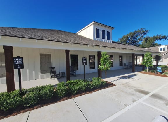 the front of a white building with a porch and a sidewalk