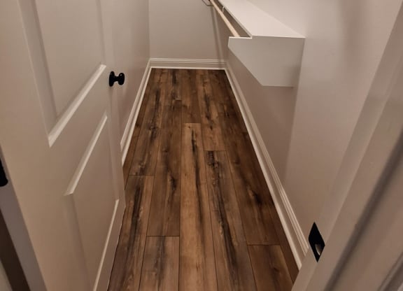 a large walk in closet with white walls and wood floors